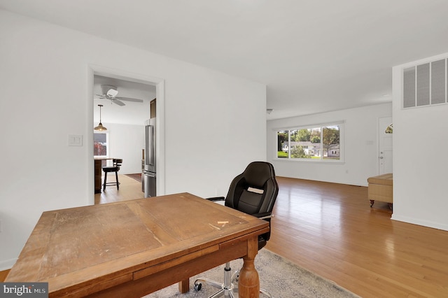 office area with light wood-style floors, ceiling fan, and baseboards