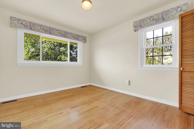 spare room featuring healthy amount of natural light, wood finished floors, and baseboards