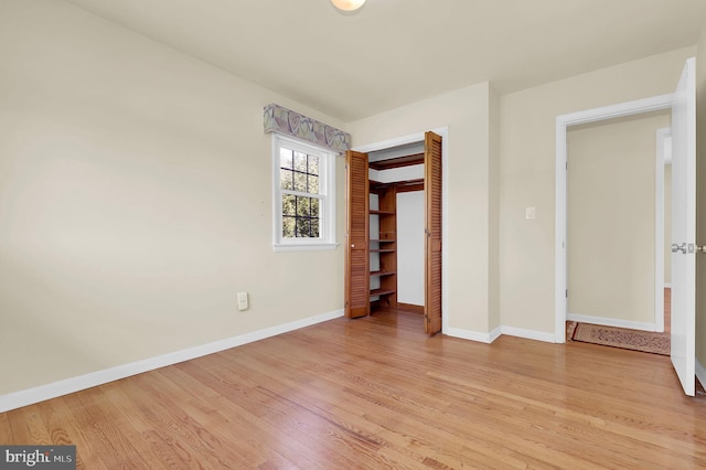 unfurnished bedroom with light wood-style flooring, baseboards, and a closet