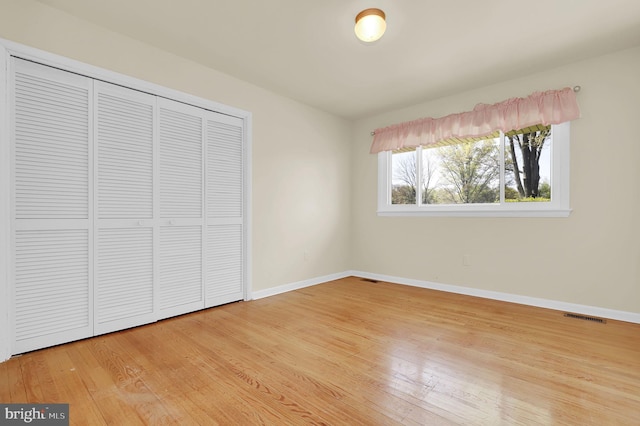 unfurnished bedroom with wood finished floors, baseboards, and a closet