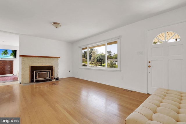 unfurnished living room with wood finished floors, plenty of natural light, a fireplace, and baseboards