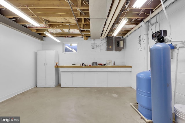 basement featuring a water pressure tank, a water softener, a workshop area, and electric panel