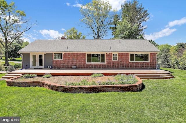 rear view of house with french doors, a wooden deck, a chimney, a lawn, and roof with shingles