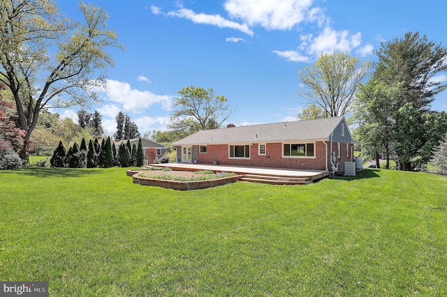 back of property featuring a lawn, brick siding, and a deck
