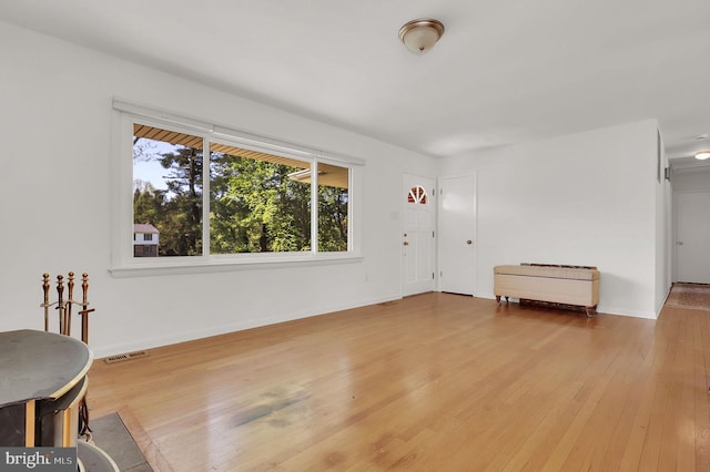 unfurnished living room with hardwood / wood-style floors and baseboards