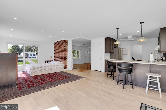 bedroom with light wood-style floors, multiple windows, recessed lighting, freestanding refrigerator, and a sink