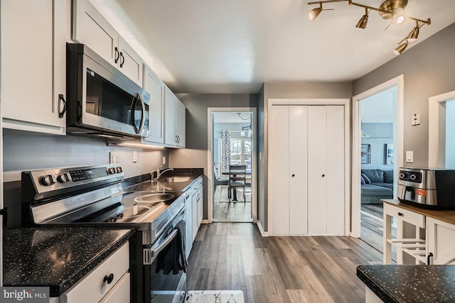 kitchen featuring appliances with stainless steel finishes, white cabinets, sink, and hardwood / wood-style flooring