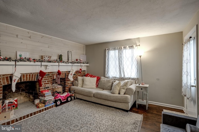 living room featuring a textured ceiling, a brick fireplace, dark wood-type flooring, and wood walls