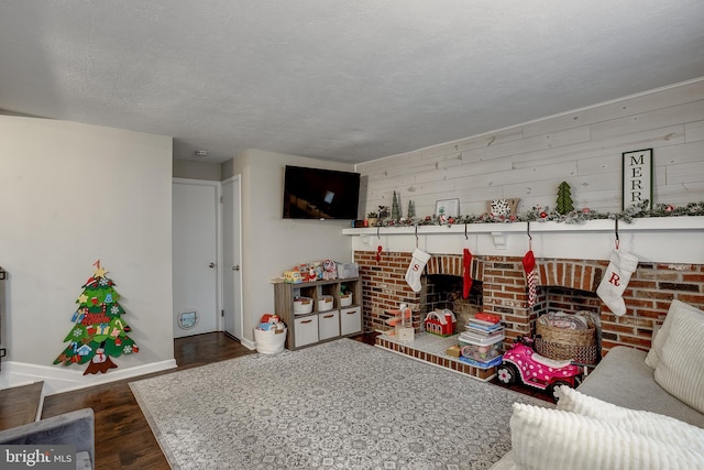 interior space with a fireplace, a textured ceiling, dark wood-type flooring, and wooden walls