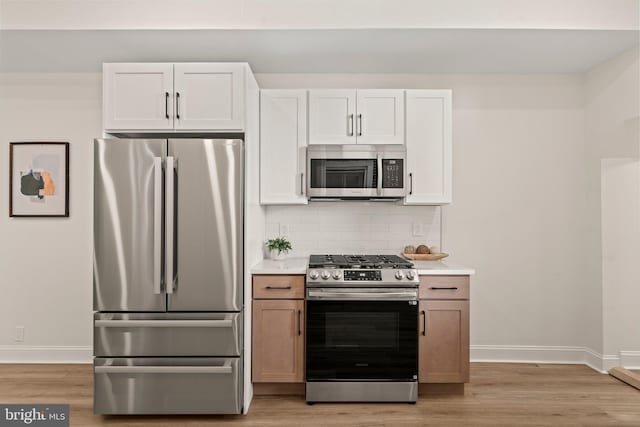 kitchen featuring decorative backsplash, white cabinets, stainless steel appliances, and light hardwood / wood-style floors