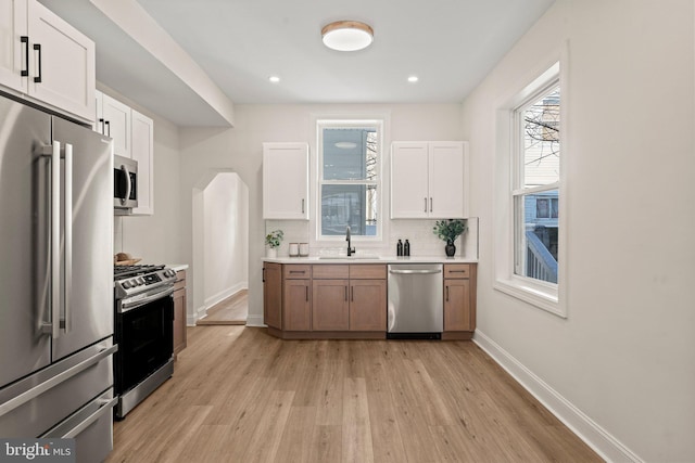 kitchen featuring white cabinets, appliances with stainless steel finishes, light hardwood / wood-style flooring, and sink