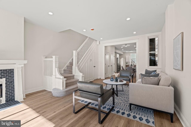 living room featuring light wood-type flooring and a tiled fireplace