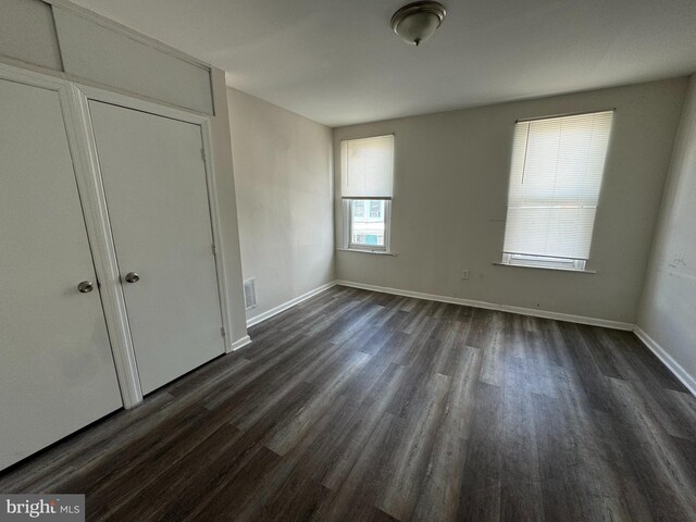 unfurnished bedroom with dark wood-type flooring and a closet