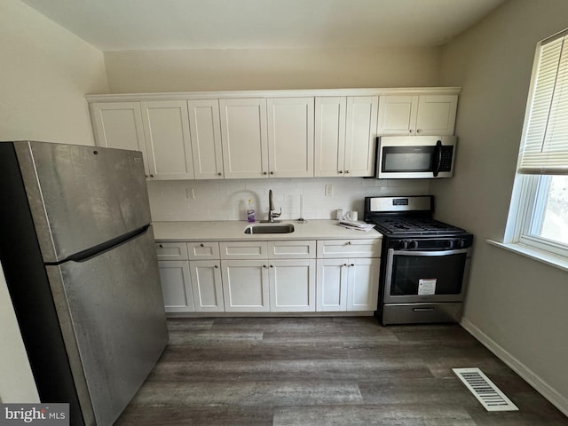 kitchen with white cabinets, sink, appliances with stainless steel finishes, and dark wood-type flooring