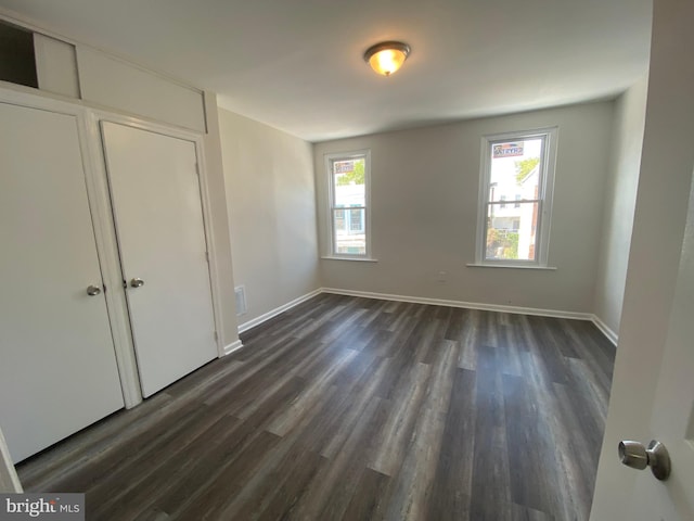 unfurnished bedroom with dark wood-type flooring and a closet