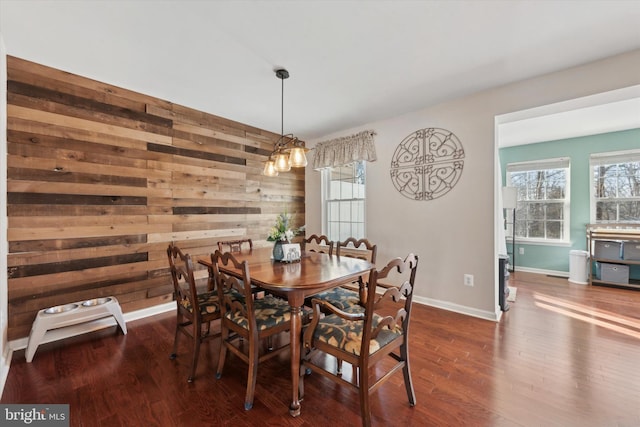 dining area with wooden walls, baseboards, and wood finished floors