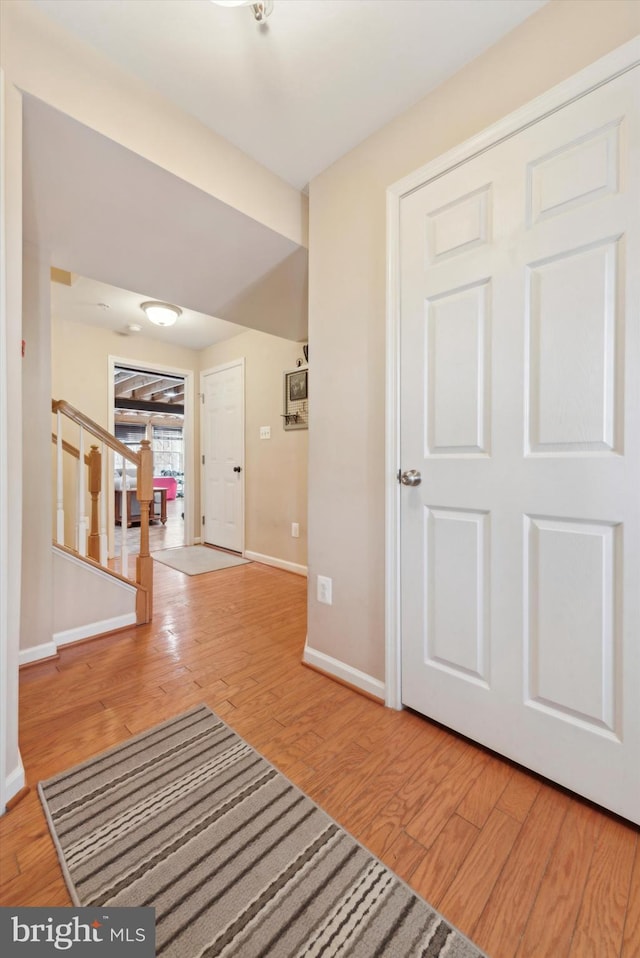 corridor featuring stairs, baseboards, and wood finished floors