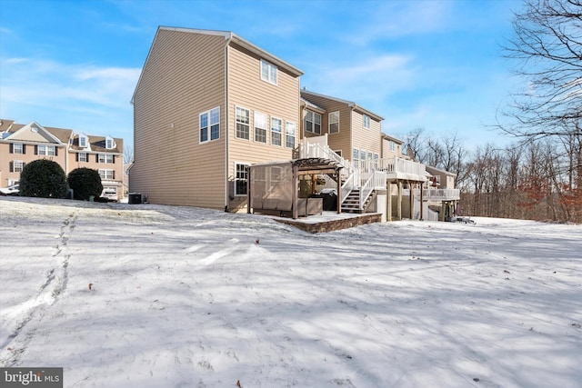 snow covered house with stairway and a deck