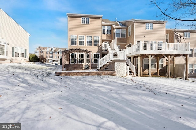 snow covered house with a residential view, stairway, a pergola, and a wooden deck