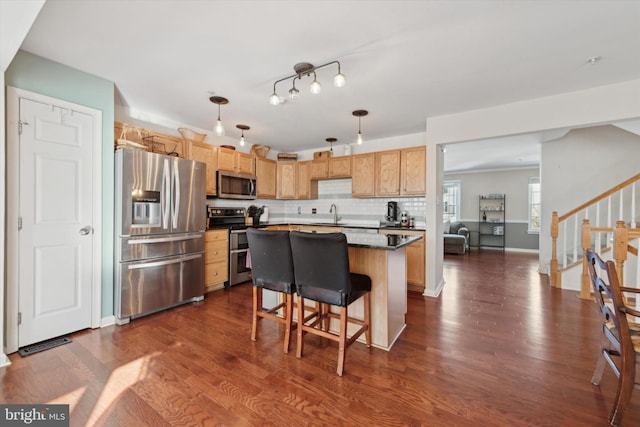 kitchen with decorative backsplash, dark wood-style floors, a breakfast bar area, a center island, and stainless steel appliances