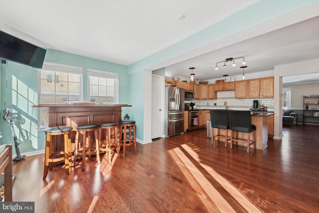 living area featuring dark wood-style floors, a bar, and baseboards