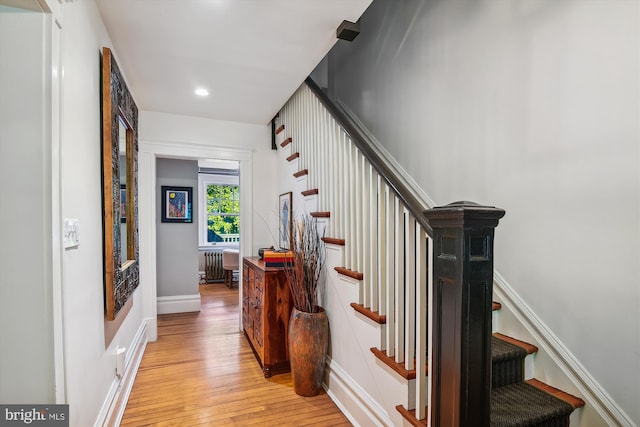 stairs featuring wood-type flooring and radiator heating unit