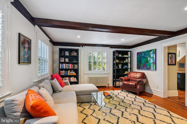 living room featuring radiator heating unit, beam ceiling, and light wood-type flooring