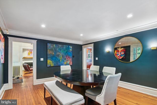 dining space featuring radiator, ornamental molding, and light hardwood / wood-style floors