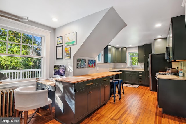 kitchen featuring a breakfast bar, light hardwood / wood-style flooring, sink, and wooden counters