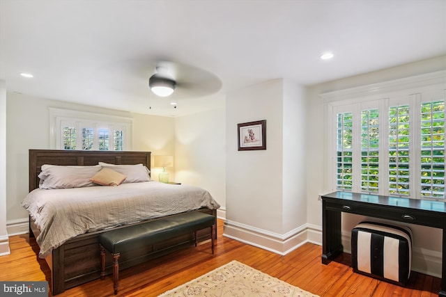 bedroom featuring ceiling fan, multiple windows, and wood-type flooring