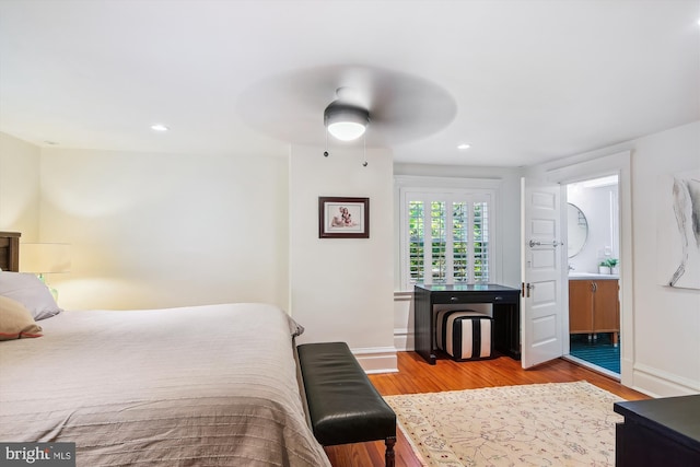 bedroom featuring ceiling fan, ensuite bath, and hardwood / wood-style flooring