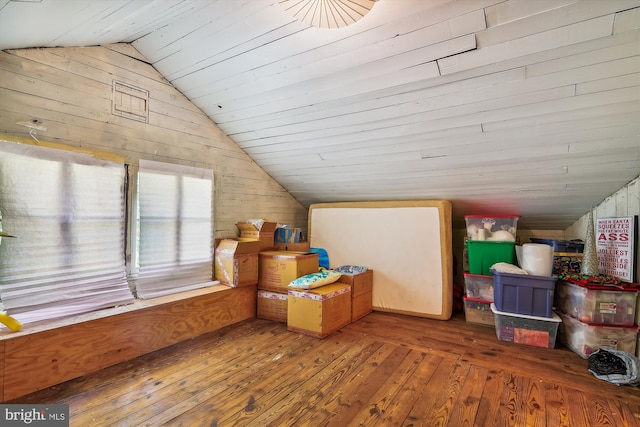 additional living space featuring vaulted ceiling, wood walls, and hardwood / wood-style flooring