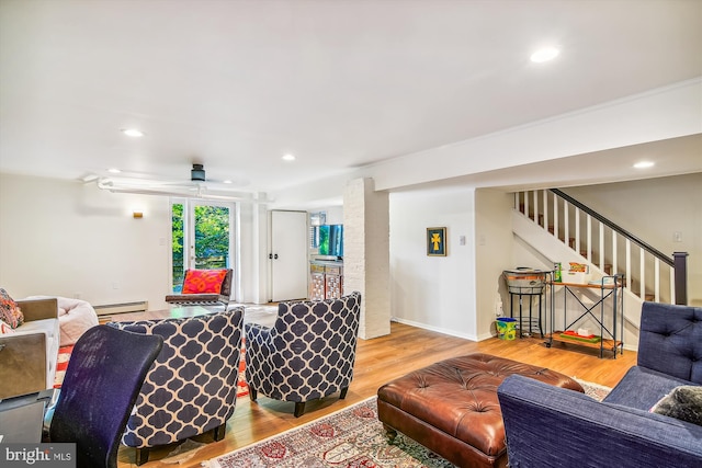 living room with a baseboard heating unit, crown molding, and hardwood / wood-style floors