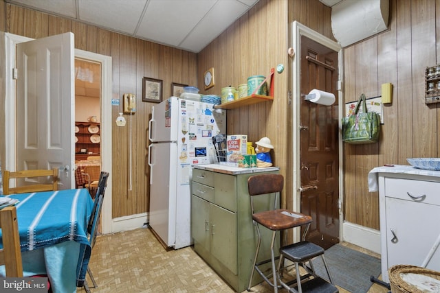 kitchen featuring wood walls, a paneled ceiling, white refrigerator, and green cabinets