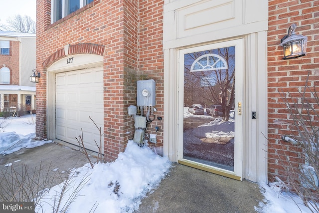 snow covered property entrance with a garage