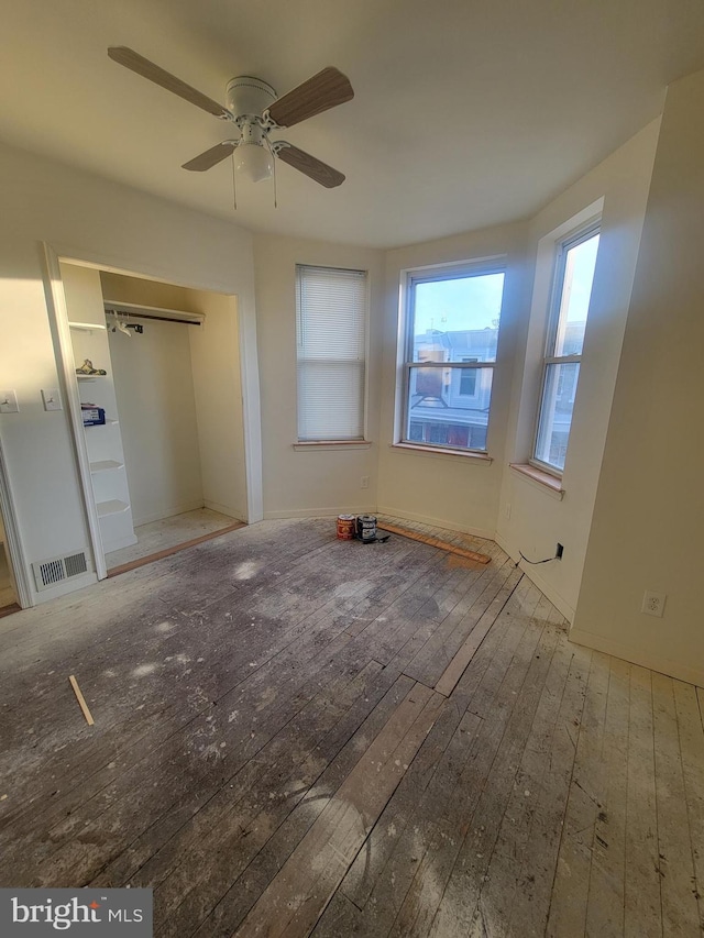 unfurnished bedroom with ceiling fan, a closet, and wood-type flooring