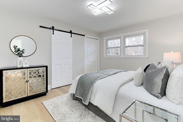 bedroom featuring a barn door and light hardwood / wood-style flooring