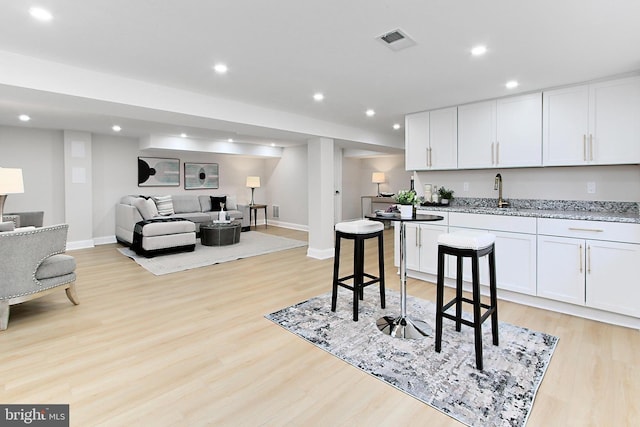 kitchen with white cabinetry, light stone counters, and light hardwood / wood-style floors