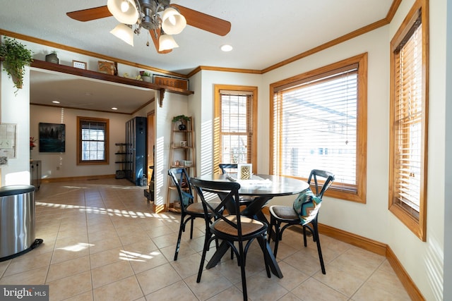 tiled dining space featuring ceiling fan and ornamental molding