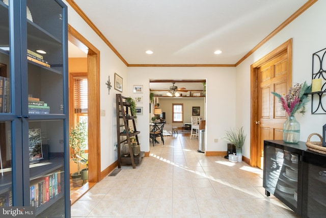 entrance foyer with ceiling fan, ornamental molding, and tile patterned floors