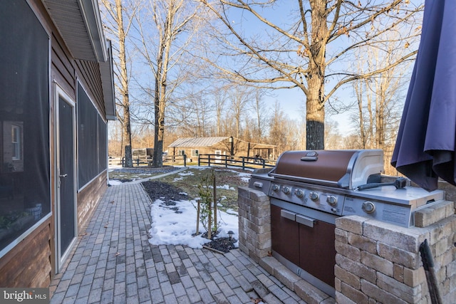 snow covered patio featuring grilling area and an outdoor kitchen