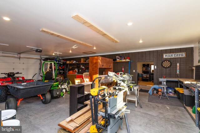 garage featuring a garage door opener, wooden walls, and a workshop area