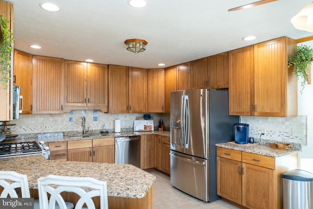 kitchen with sink, light tile patterned floors, appliances with stainless steel finishes, kitchen peninsula, and backsplash