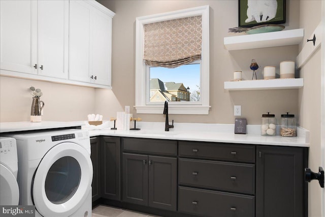 laundry room with sink, washer and clothes dryer, and cabinets