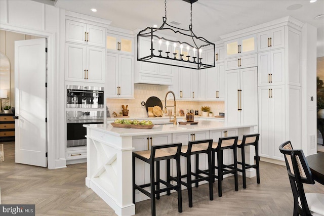 kitchen featuring a center island with sink, light parquet flooring, and white cabinetry