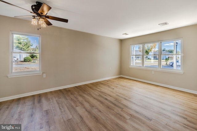 empty room featuring ceiling fan, plenty of natural light, and light wood-type flooring