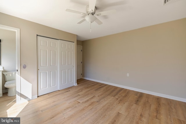 unfurnished bedroom featuring a closet, ensuite bathroom, light hardwood / wood-style flooring, and ceiling fan