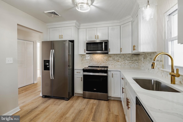 kitchen featuring light stone countertops, white cabinetry, sink, and appliances with stainless steel finishes