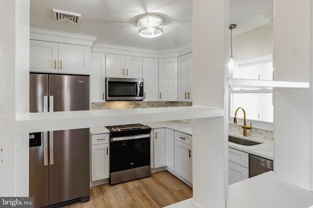 kitchen with sink, white cabinets, decorative light fixtures, and appliances with stainless steel finishes