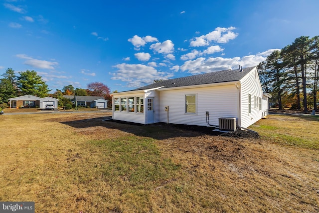 rear view of house with a lawn, central air condition unit, and a sunroom